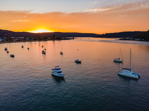 Aerial sunrise waterscape over the channel with orange clouds and boats below